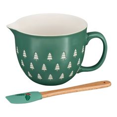 a green mug and spatula with trees on it