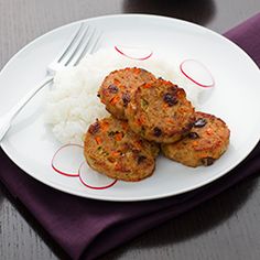 a white plate topped with meat patties and rice next to a bowl of sauce