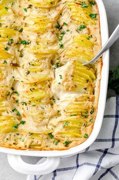 a casserole dish with potatoes and parsley in it on a blue towel