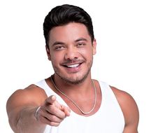 a man in white tank top pointing at the camera with his right hand and smiling