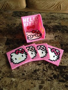 four pink hello kitty coasters sitting on top of a table next to a couch