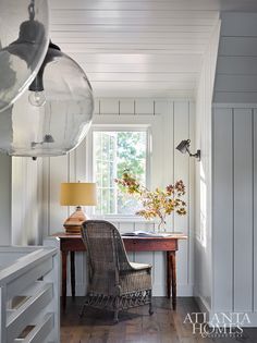 a chair sitting in front of a desk with a lamp on it next to a window