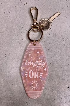 a pink keychain with the words everything will be ok written in white on it