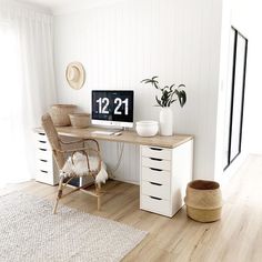 a desk with a clock on it next to a chair and potted plant in the corner