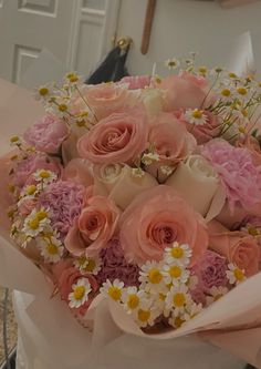 a bouquet of pink roses and daisies on a table