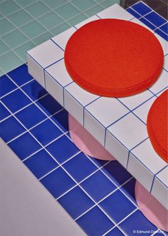 two red and white round cushions sitting on top of a blue tiled floor next to each other