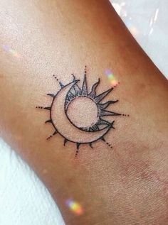 a small sun and moon tattoo on the wrist is shown in black ink with white dots