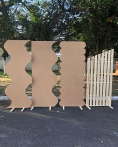 three pieces of cardboard sitting next to each other on the ground in front of a fence