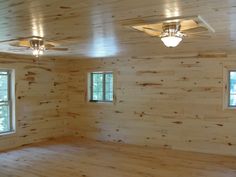 an empty room with windows and ceiling fan in the center, surrounded by wood planks