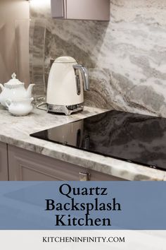 a kitchen with marble counter tops and gray cabinets, including an electric kettle on the stove