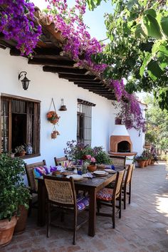 an outdoor dining area with potted plants and flowers on the wall, next to a fireplace