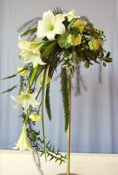 a vase filled with flowers and greenery on top of a table