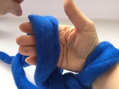 a person is holding something in their hand with blue yarn wrapped around the thumbnails