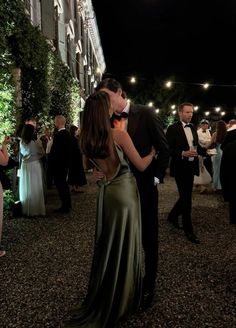 a man and woman are kissing in front of some people at an outdoor dinner event