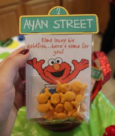 a hand holding up a package of cheetos from sesame street, which is for sale