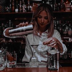 a woman is making a drink at the bar