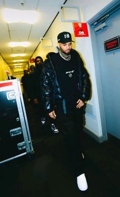 a man in black jacket and hat walking down hallway