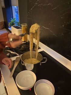 a person stirring food in a pot on the stove