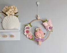 there is a wall decoration with flowers and a doll hanging from it's side