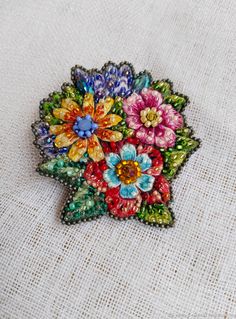 a colorful flower brooch sitting on top of a white cloth