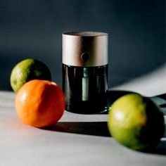 three oranges and two limes sitting on a table next to an electric juicer