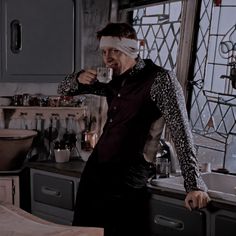 a woman with bandages on her head standing in a kitchen next to a sink and window