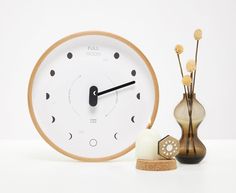 a white clock sitting on top of a table next to vases