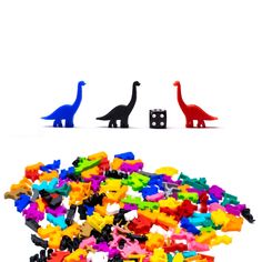 three toy dinosaurs standing next to each other in front of a pile of lego blocks