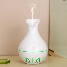 a white vase sitting on top of a table next to a green slice of lime