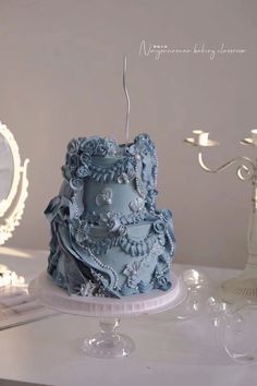 a blue cake sitting on top of a table next to a mirror and candle holder