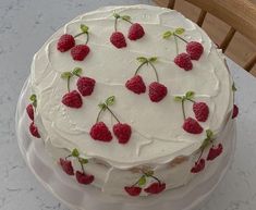 a cake with white frosting and raspberries on it sitting on a table