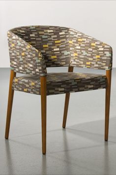 a chair with wooden legs and a patterned upholstered backrest, in an empty room