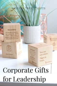 three wooden blocks with the words corporate gifts for leaders on them, sitting next to a potted plant