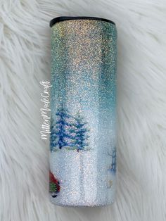 a blue and white tumbler with trees on it sitting on top of a fur rug