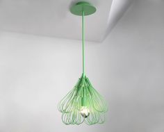 a green lamp hanging from the ceiling in a room with white walls and flooring