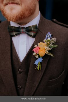 a man in a suit and bow tie wearing a boutonniere with flowers on the lapel