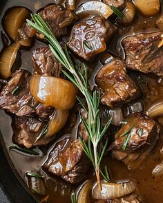 beef stew with onions and carrots in a black pot on the stove top, ready to be eaten