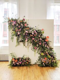 an arrangement of flowers and greenery on a wall