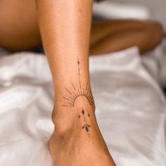 a woman's foot with a sun and stars tattoo on her left side leg