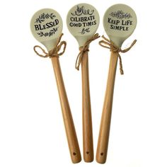 three wooden spoons with words on them are tied up to each other and placed next to each other