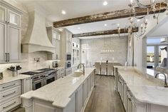 a large kitchen with white cabinets and marble counter tops