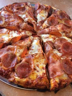 a pizza with pepperoni and cheese cut into four slices on a platter, ready to be eaten