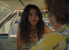 a woman sitting in the back seat of a car talking to a man who is looking at her