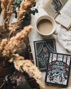 an open book sitting on top of a table next to a cup of coffee