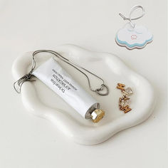 a white tray with a keychain, bottle and charms on it next to a tag