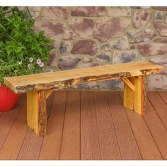 a wooden bench sitting on top of a hard wood floor next to a potted plant