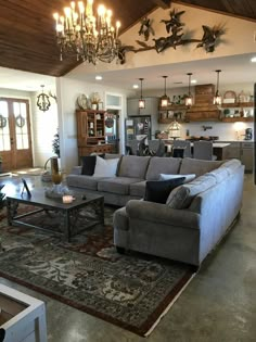 a living room filled with furniture and a chandelier hanging above the couches