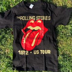 the rolling stones t - shirt laying on grass with its tongue painted onto it's chest