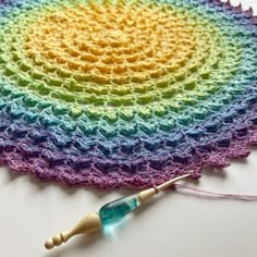 a crocheted rainbow doily with a knitting needle