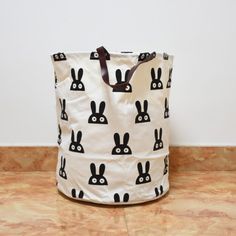 a white bag with black rabbits on it sitting on the floor next to a wall